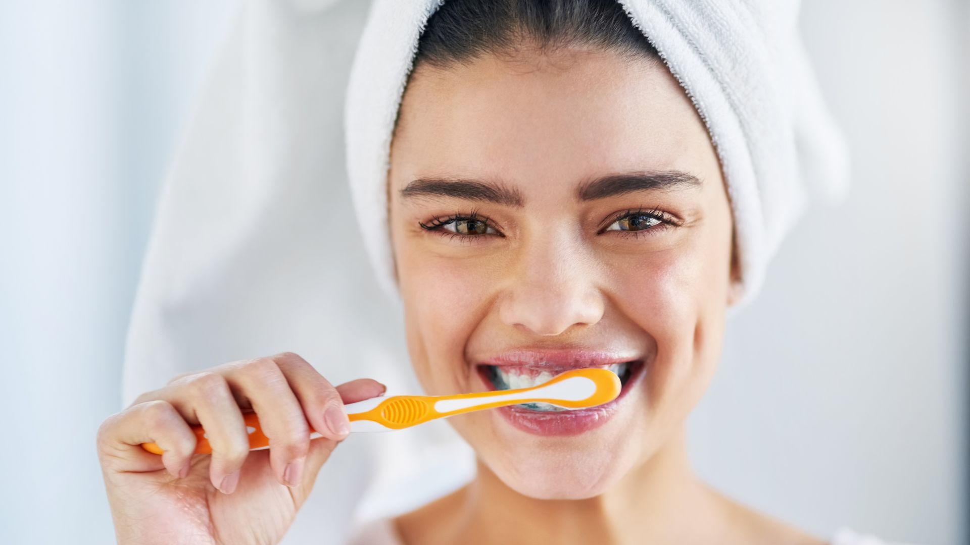 mujer cepillándose los dientes y sonriendo