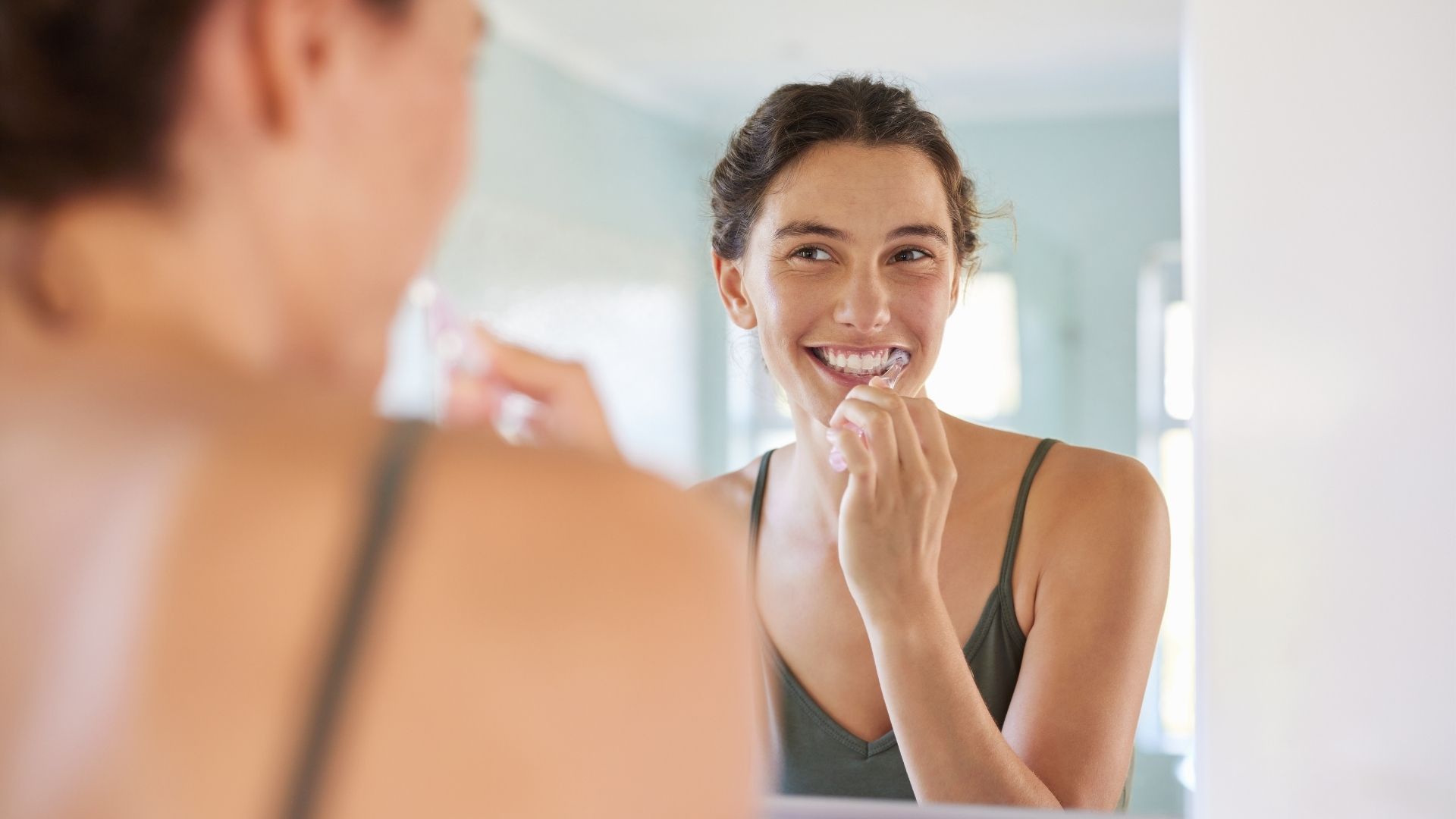 Mujer cepillándose los dientes delante del espejo